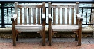 Wooden benches by a waterfront railing.