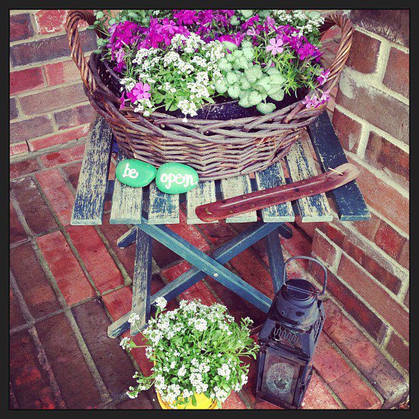 Rustic outdoor corner with flowers and vintage decor on a brick patio.
